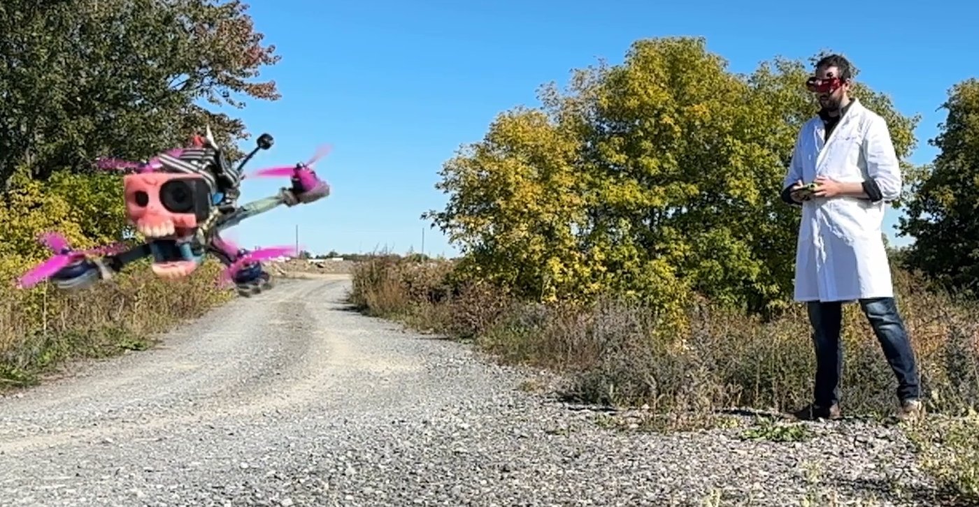 FPV drone with denture canopy in flight, pilot in lab coat and FPV goggles on a country road